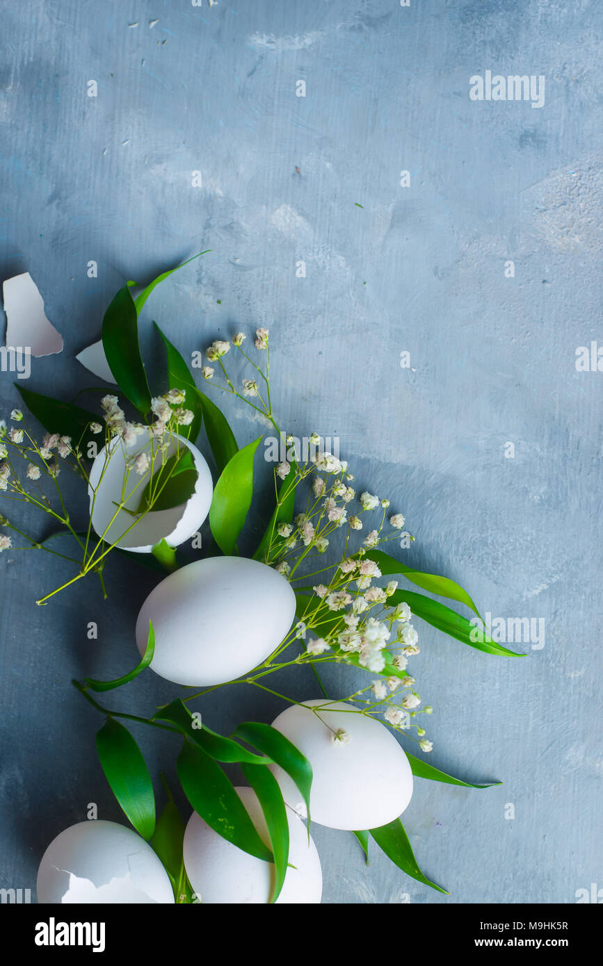 Sovraccarico di sfondo di Pasqua con le uova bianche, decorativo foglie verdi e fiori di primavera. Cucina organica concetto. Foto Stock