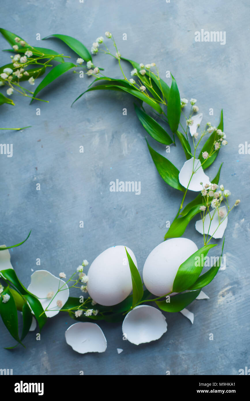 Vingette cerchio bianco con le uova di Pasqua, decorativo foglie verdi e fiori di primavera. Cucina organica concetto con copia spazio. Foto Stock