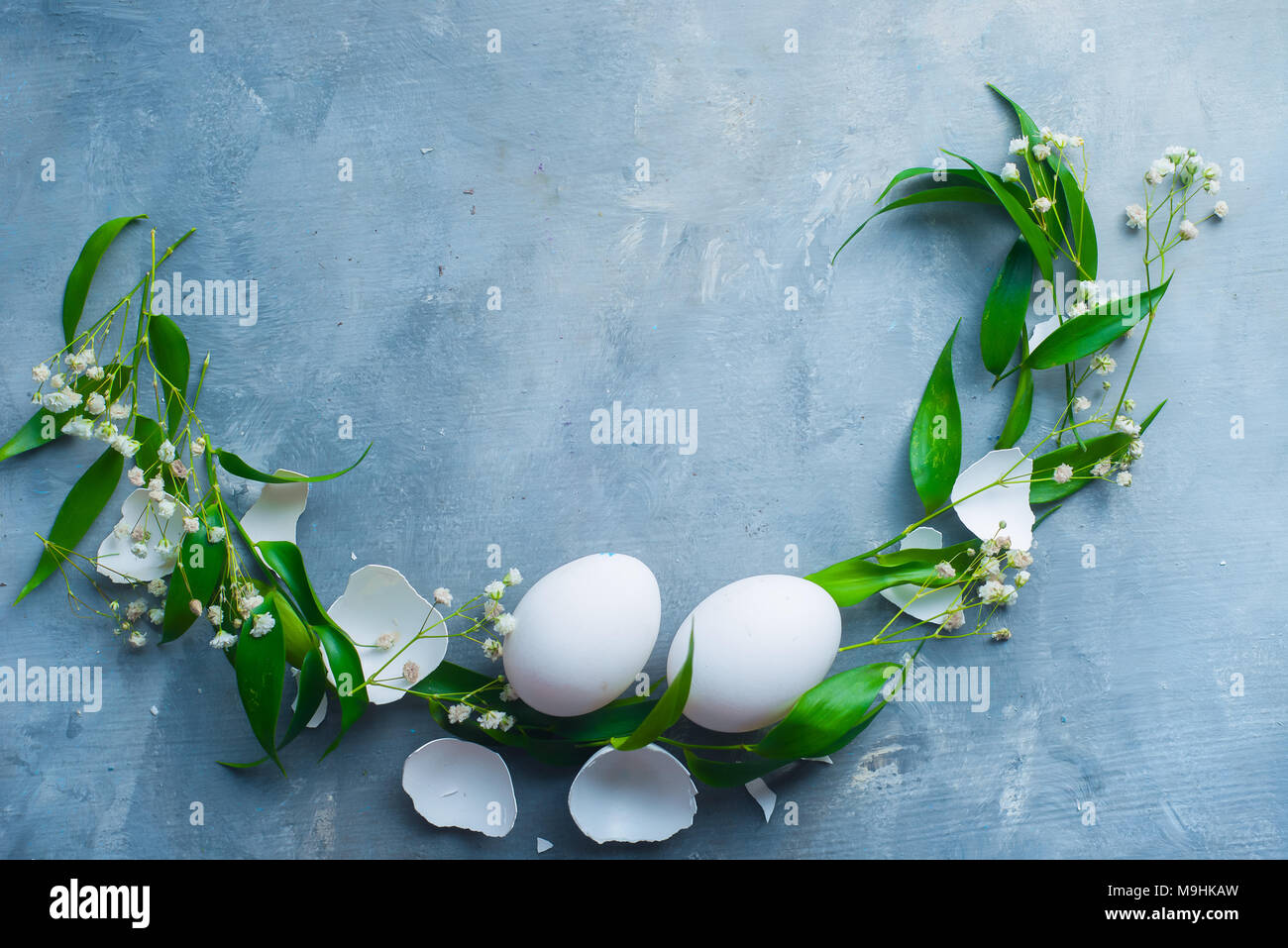 Vingette cerchio bianco con le uova di Pasqua, decorativo foglie verdi e fiori di primavera. Cucina organica concetto con copia spazio. Foto Stock
