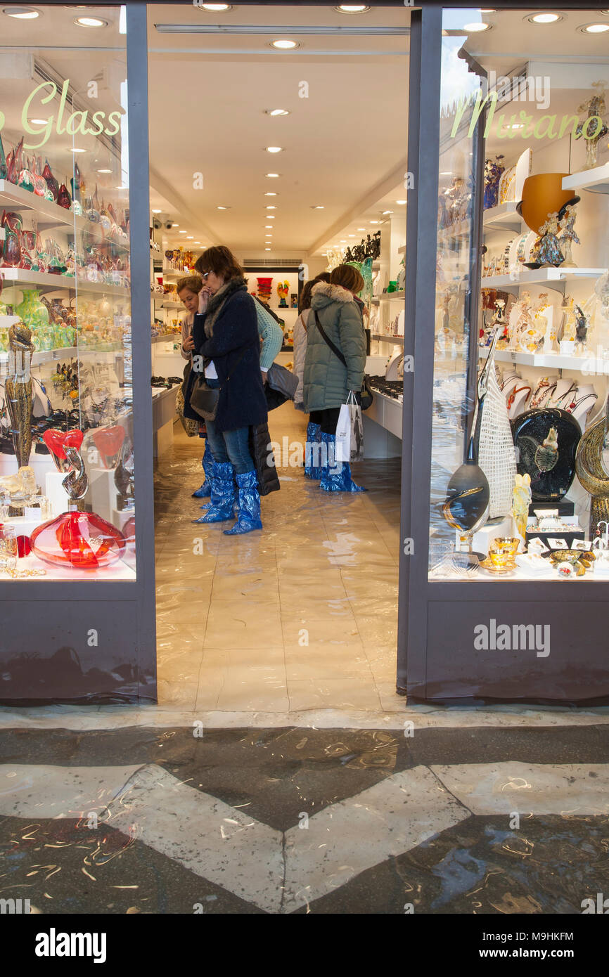 I turisti a fare shopping all'interno dell'allagato in vetro di Murano store durante l'Acqua Alta inondazioni (alta marea), Piazza San Marco (Piazza San Marco), Venezia, Veneto, Ita Foto Stock
