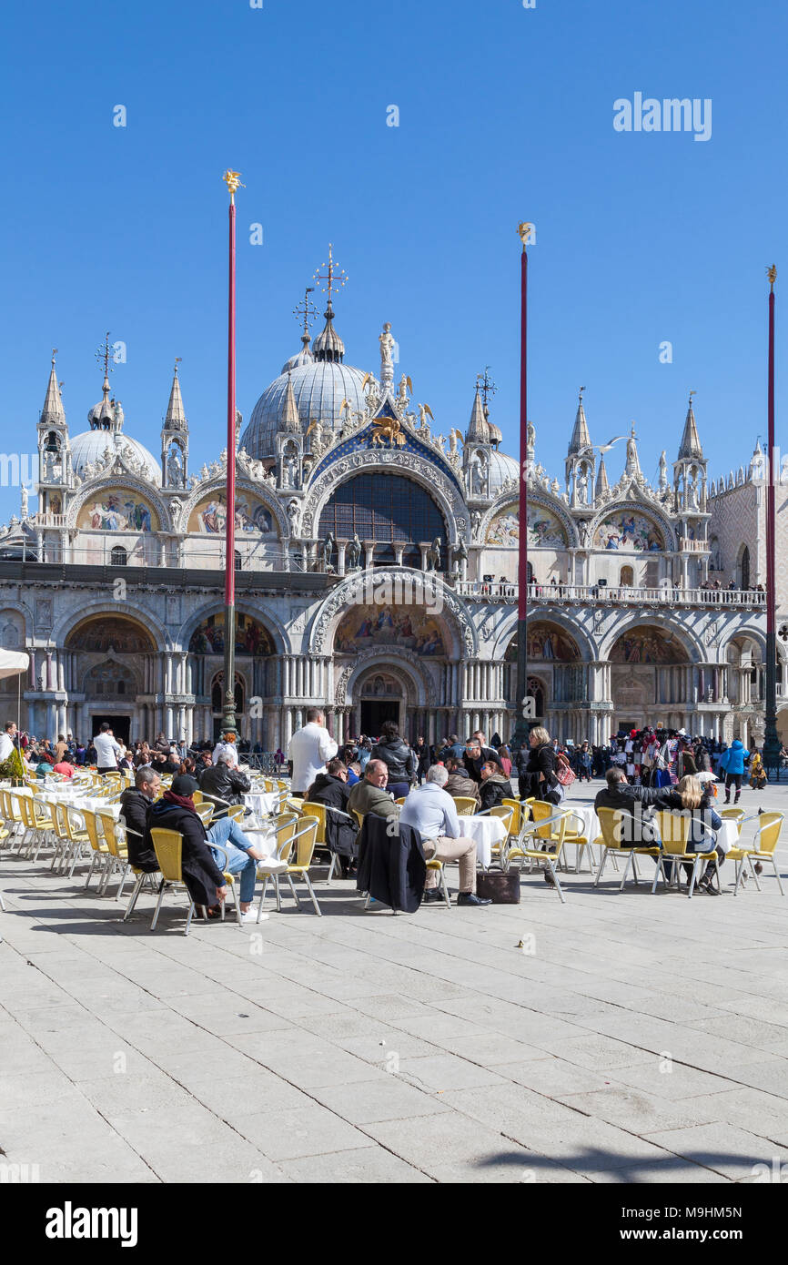 Le persone che si godono il pranzo in Piazza San Marco (Piazza San Marco), Venezia, Italia davanti alla Basilica di San Marco (Basilica di San Marco) su un soleggiato blue sky giorno Foto Stock