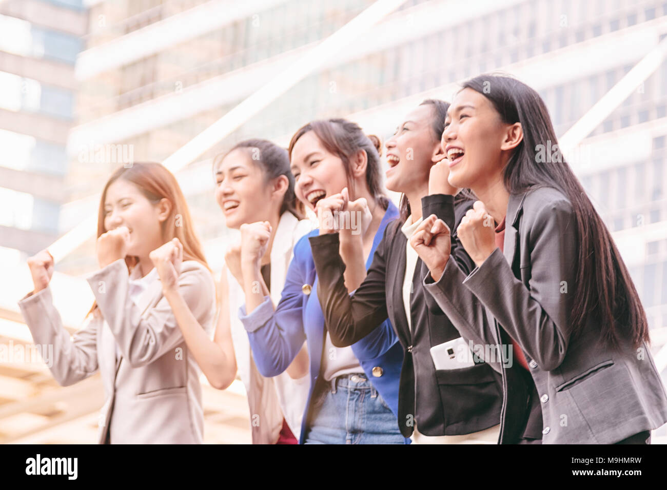 Gruppo di imprenditrici team conquista il successo con il braccio sollevato per celebrare un buon lavoro. Foto Stock