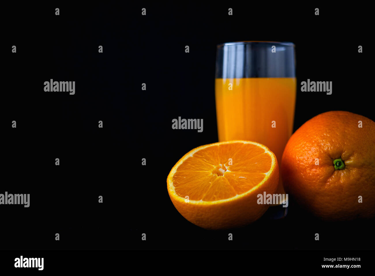 Arancione di frutta e succhi di frutta isolato su sfondo nero. Cibo scure della fotografia. Foto Stock