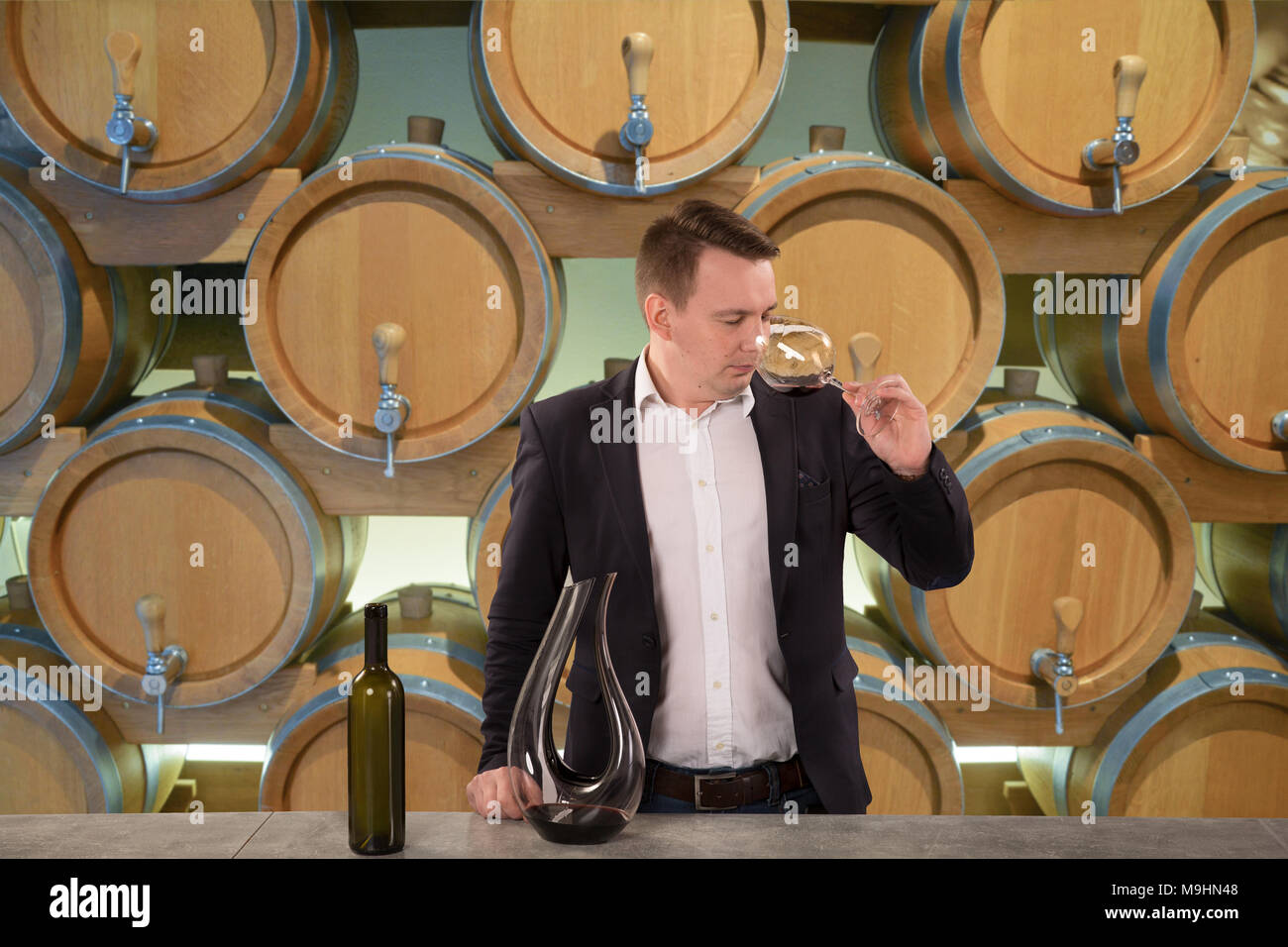 Giovane uomo bello sommelier degustazione vino rosso in cantina Foto Stock