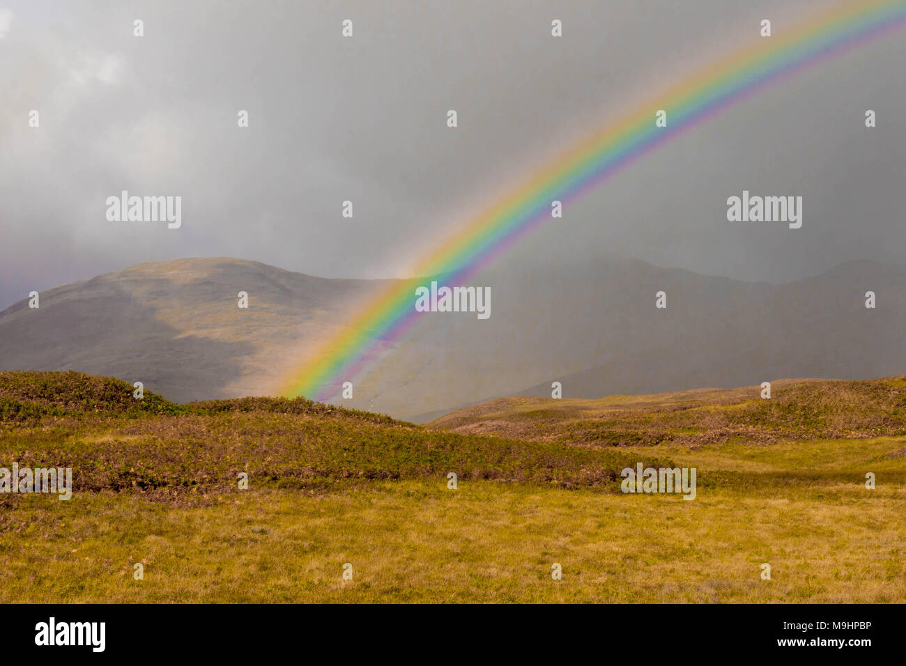Nuvoloso Rainbow nelle Highlands scozzesi Foto Stock