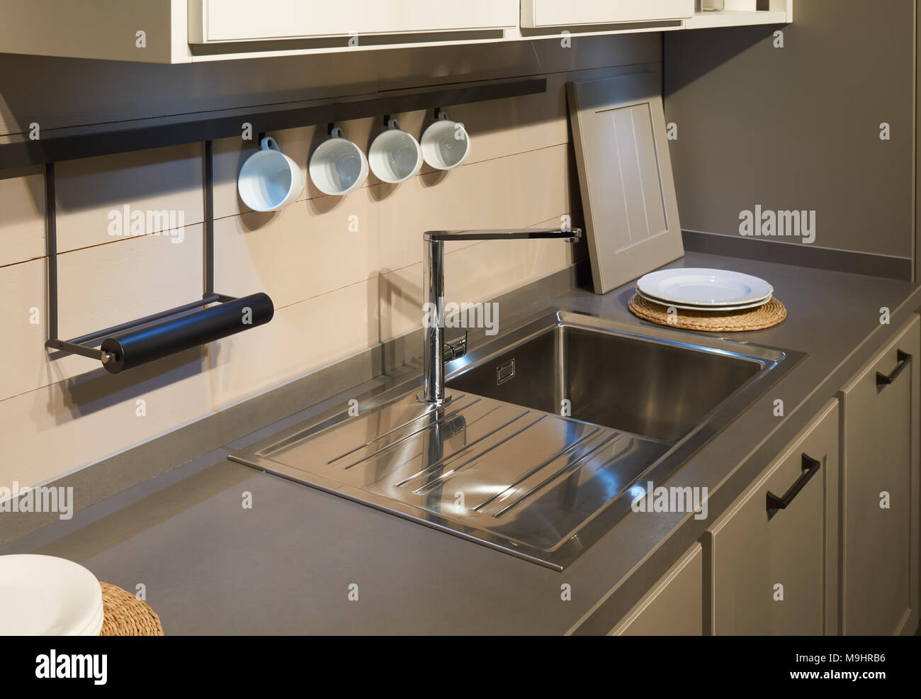 Mobili per cucina, ancora in acciaio inox lavello, miscelatore di metallo e qualche bianco stoviglie in ceramica Foto Stock
