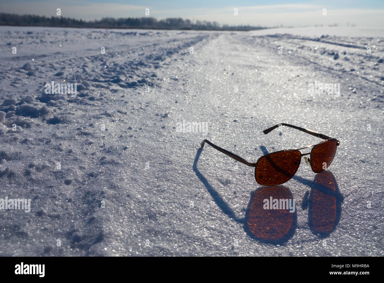 Occhiali da sole sulla neve con una bella e soleggiata scena invernale Foto Stock