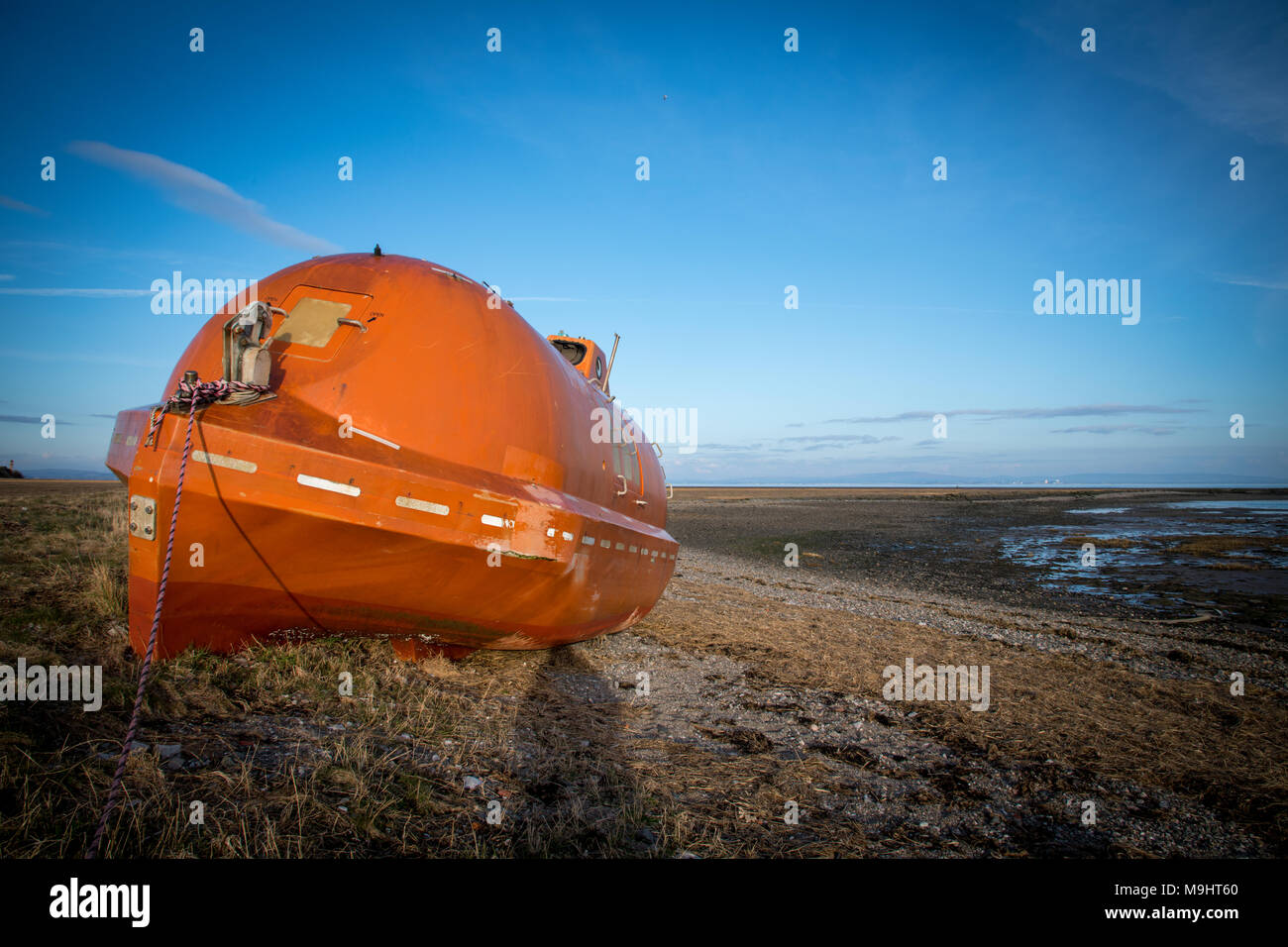 Un vecchio, abbandonato, orange life boat sinistra sulla spiaggia tra Rampside e Roa vicino a Barrow-in-Furness, Cumbria. Foto Stock