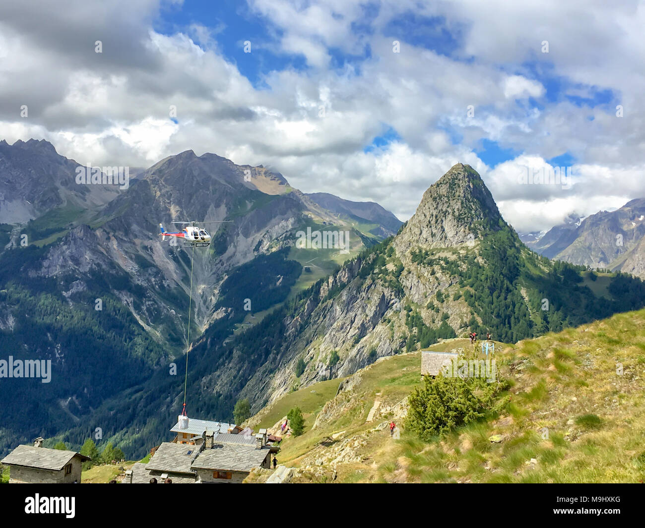 Elicottero il trasporto di materiale da costruzione nelle Alpi vicino a Courmayeur, Italia Foto Stock