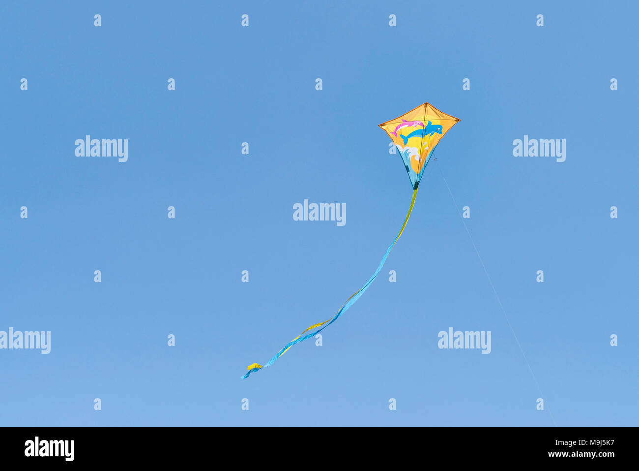 Un colorato aquilone volare contro un blu cielo senza nuvole. Foto Stock
