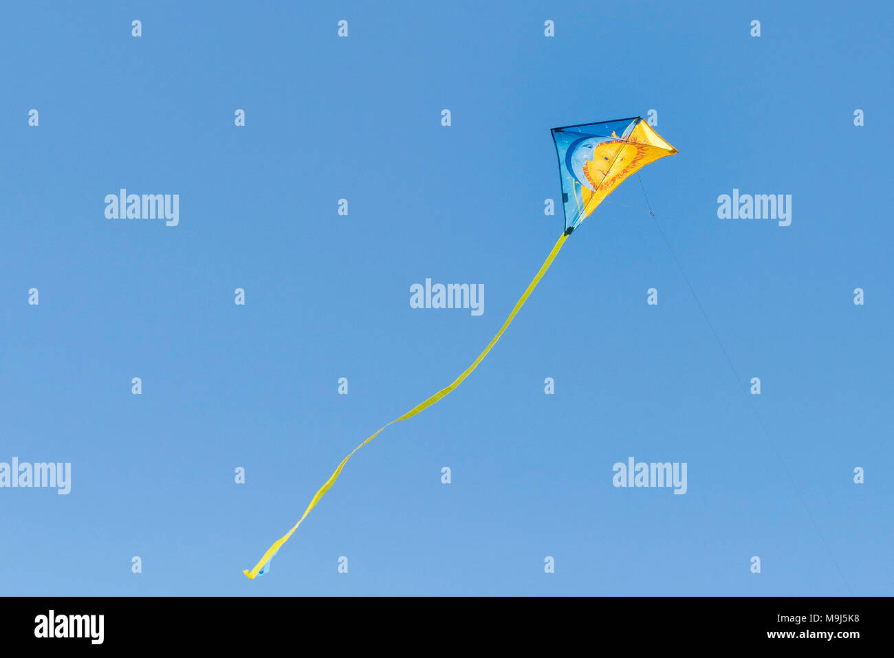 Un colorato aquilone volare contro un blu cielo senza nuvole. Foto Stock