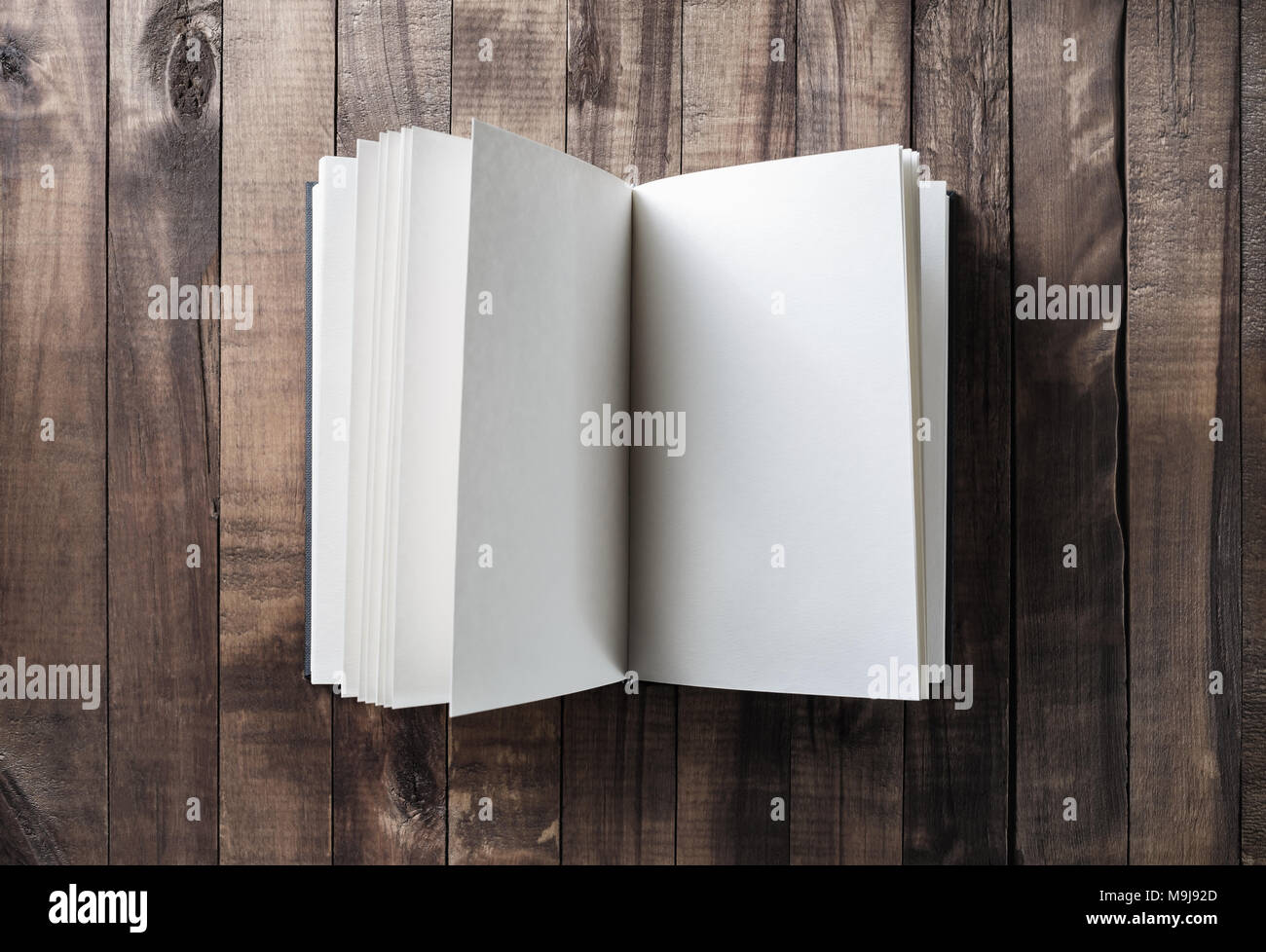 Foto del libro aperto con le pagine bianche su sfondo di legno. Vista dall'alto. Foto Stock
