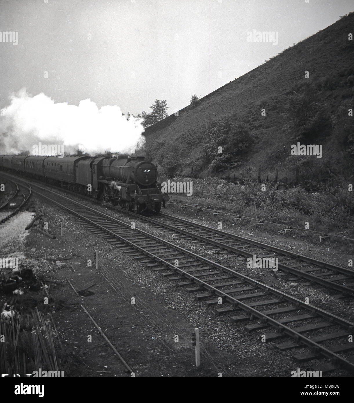 Degli anni Cinquanta, storico, una locomotiva a vapore e carrozze ferroviarie su una ferrovia, via, Inghilterra, Regno Unito. Foto Stock