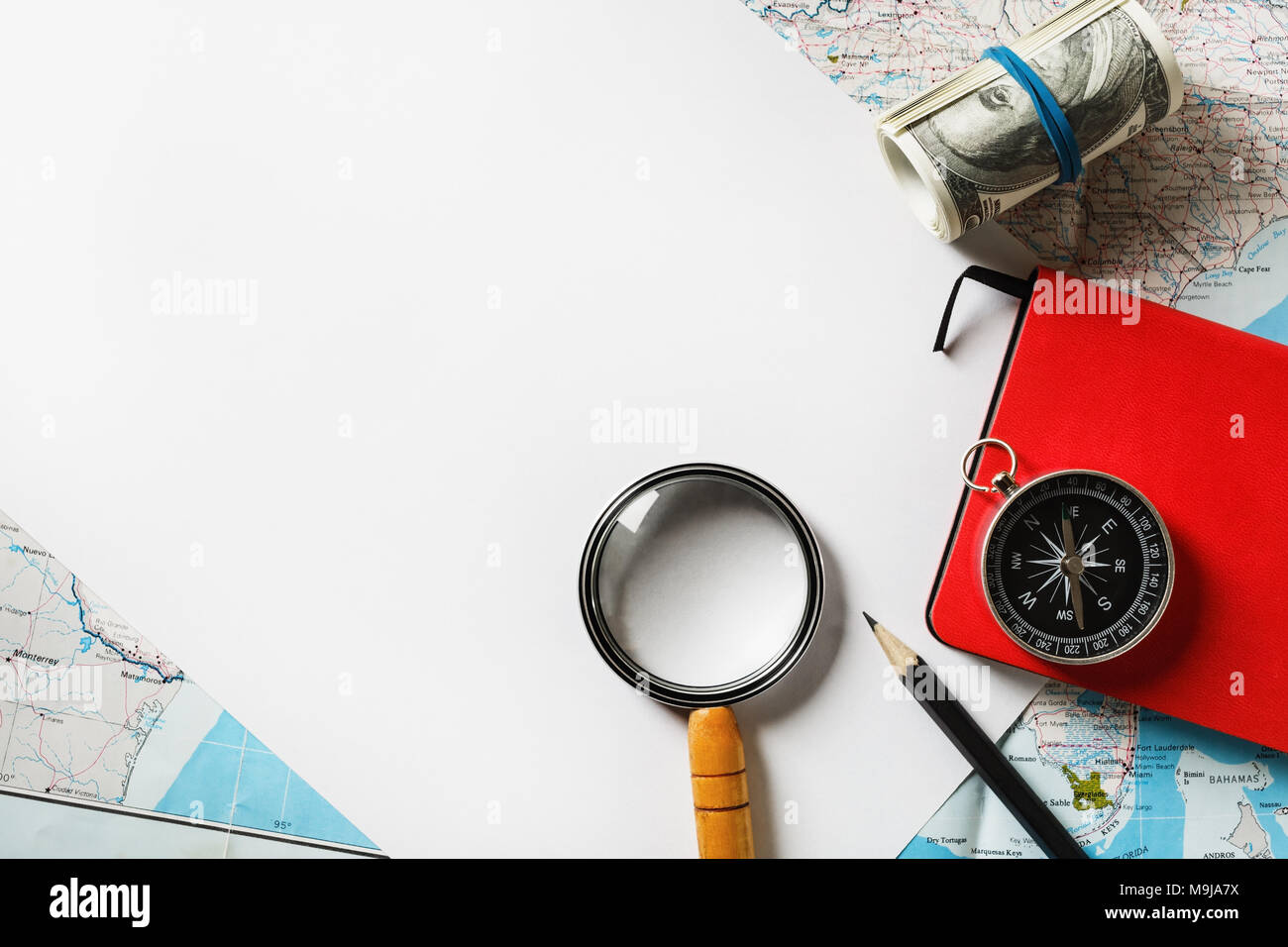 Cartoleria viaggi mockup. Carta, Magnifier, mappa, bussola, denaro notebook e matita. Lay piatto. Foto Stock