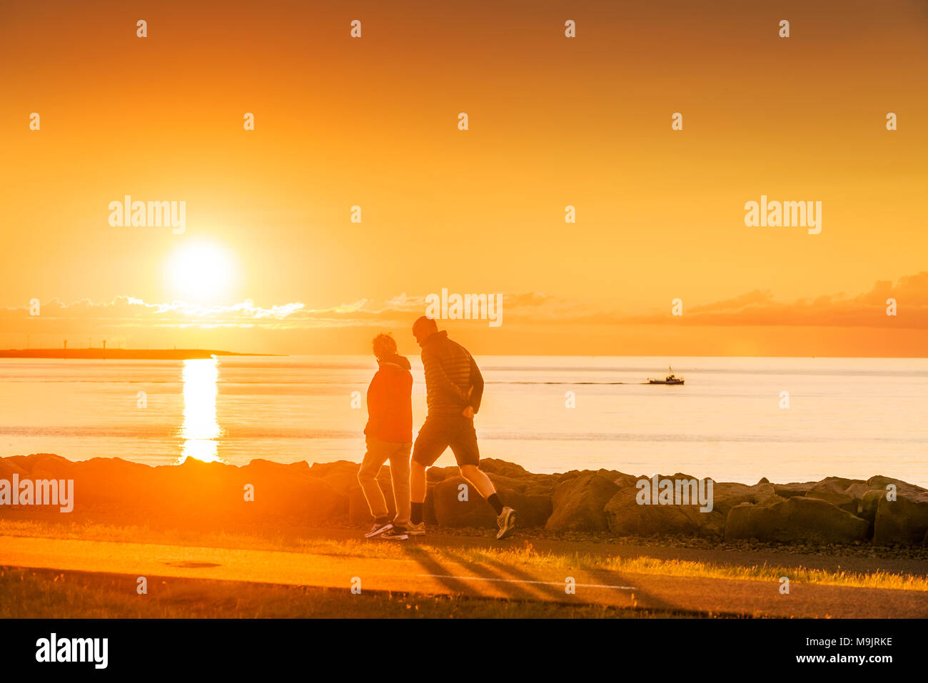 La gente camminare al tramonto sul mare, Saebraut, Reykjavik, Islanda Foto Stock