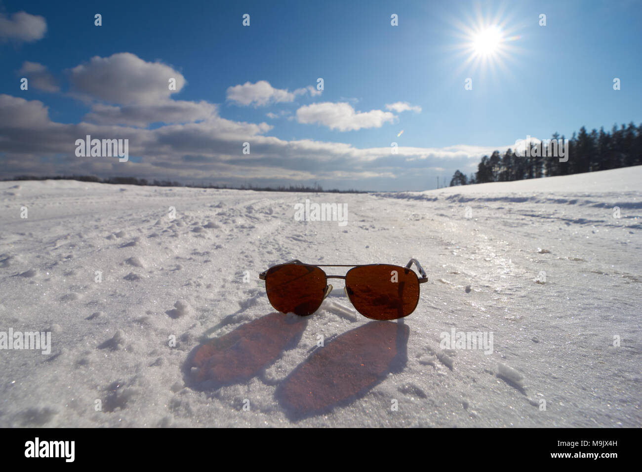 Occhiali da sole sulla neve con una bella e soleggiata scena invernale Foto Stock