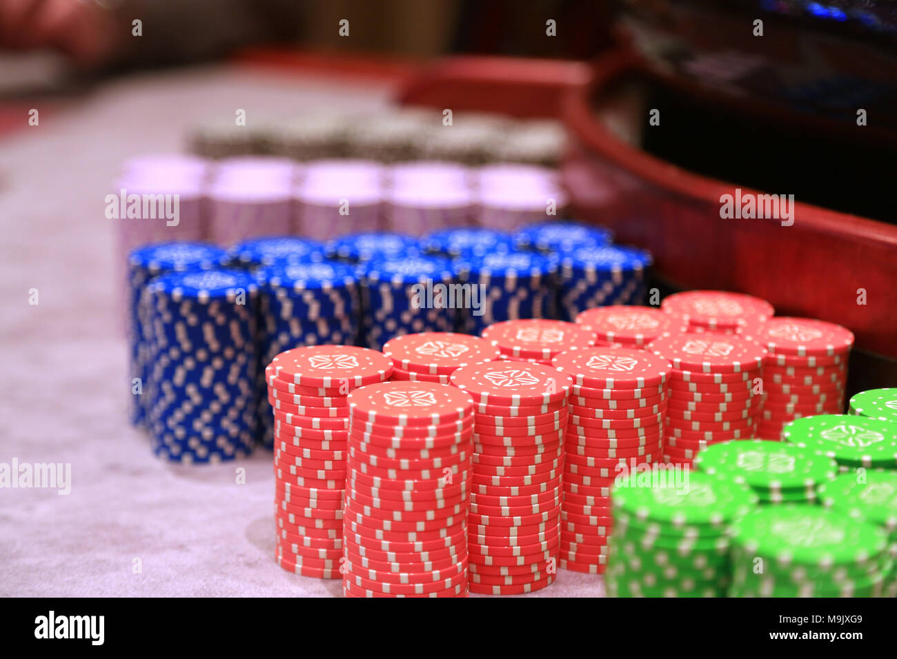Poker chips colorati pezzi di gioco giacciono sul tavolo da gioco in pila Foto Stock