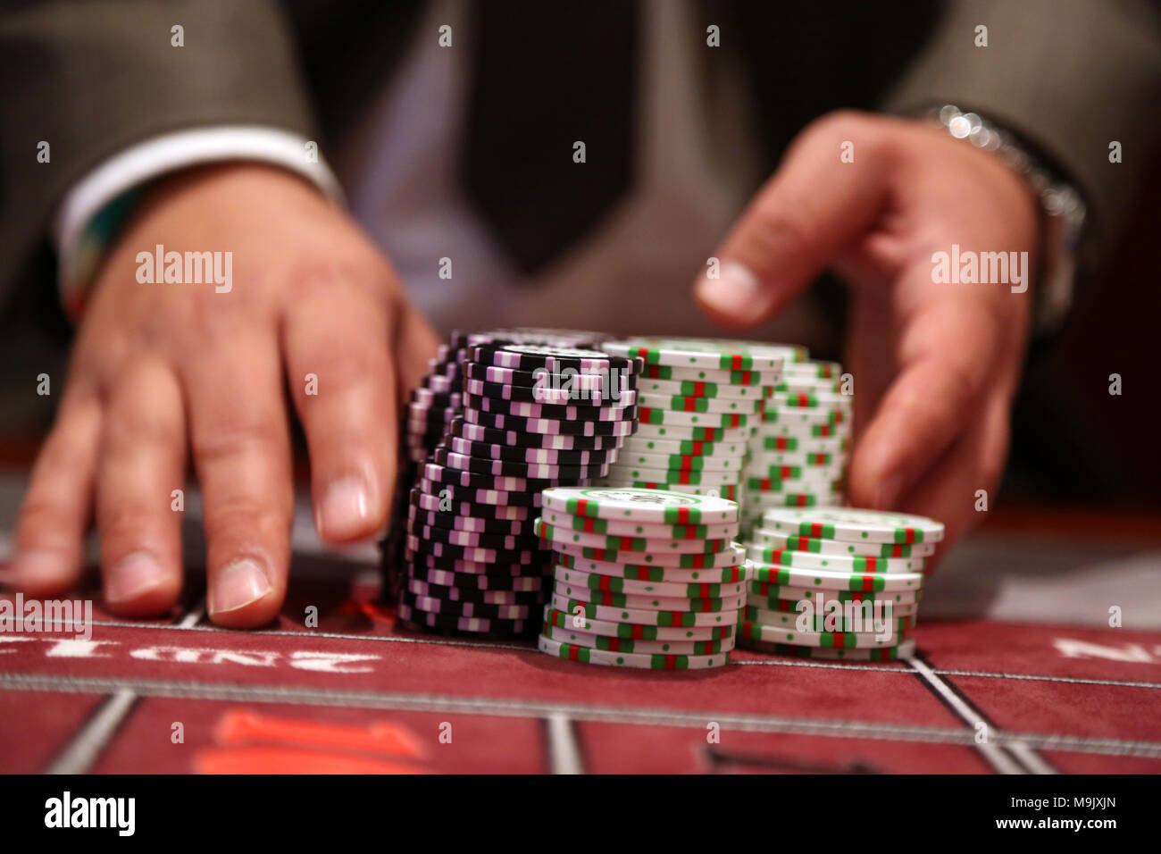 Giocatore al tavolo da gioco pusing grande pila di chip Foto Stock