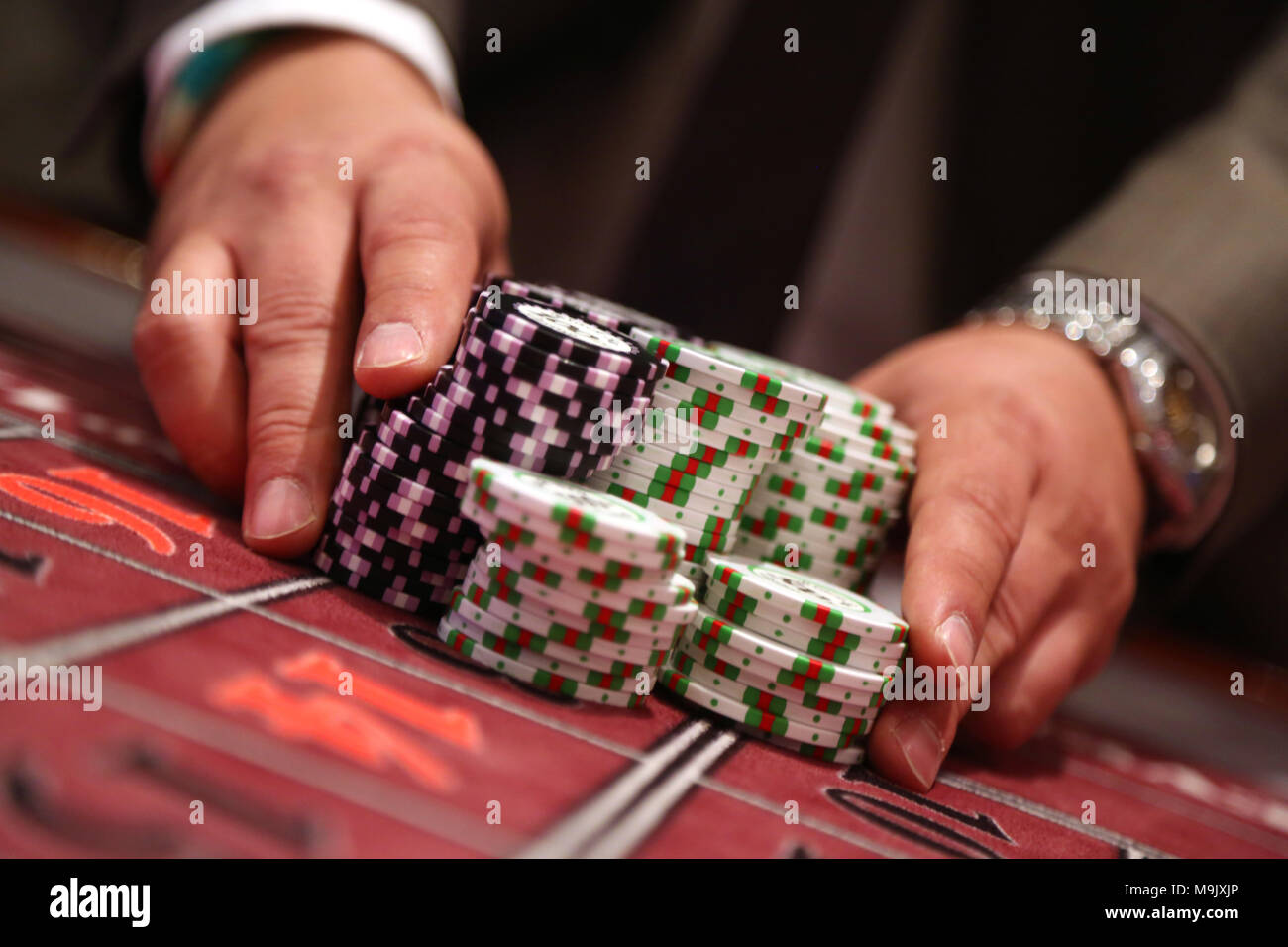 Giocatore al tavolo da gioco pusing grande pila di chip Foto Stock