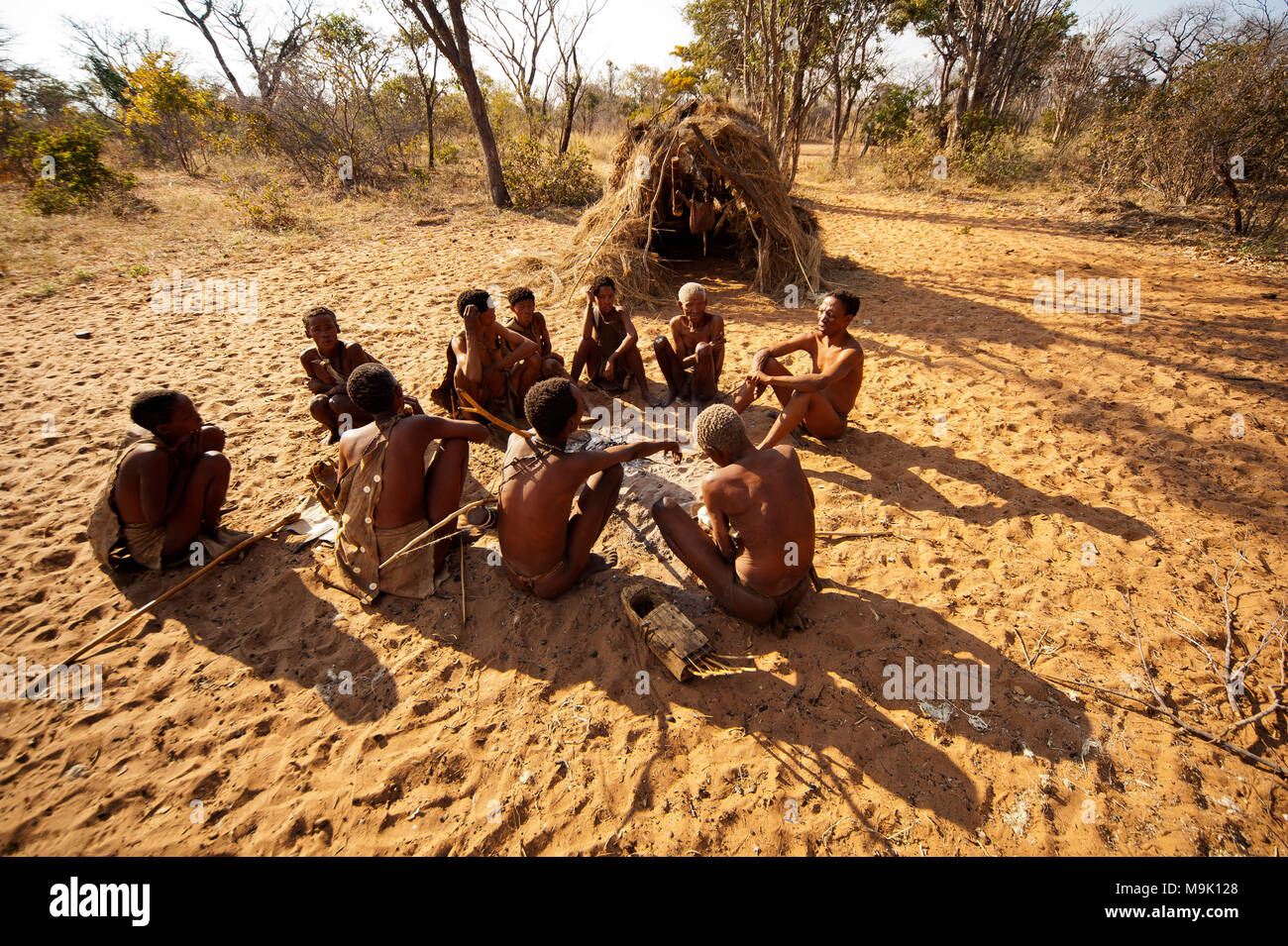 Ju/'Hoansi o Boscimani cacciatori intorno al falò presso il loro villaggio, Grashoek, Namibia Foto Stock