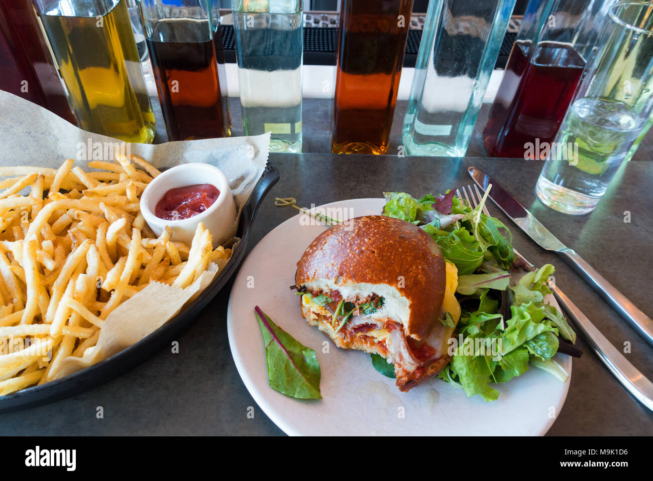 Uova e bacon sandwich su un soffice rotolo tostato con insalata mista e patatine Foto Stock