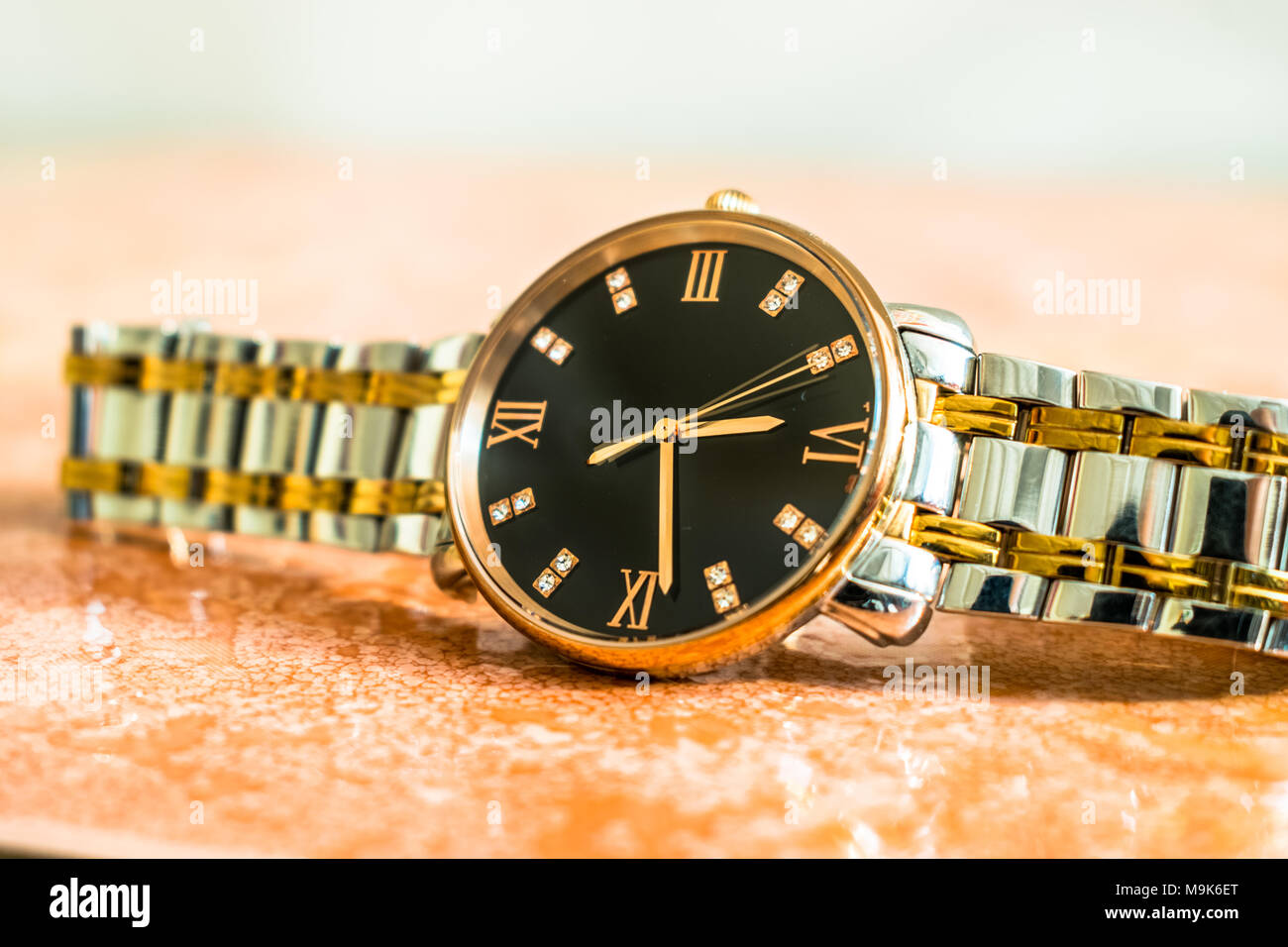Un costoso ed elegante nuovo di zecca d'argento e d'oro uomo sottile dial watch mantenuta su un pavimento di marmo Foto Stock