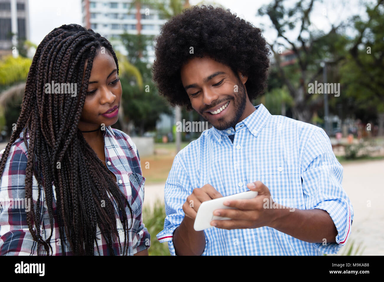 African American hipster uomo mostrando le immagini al telefono all'aperto nella città Foto Stock