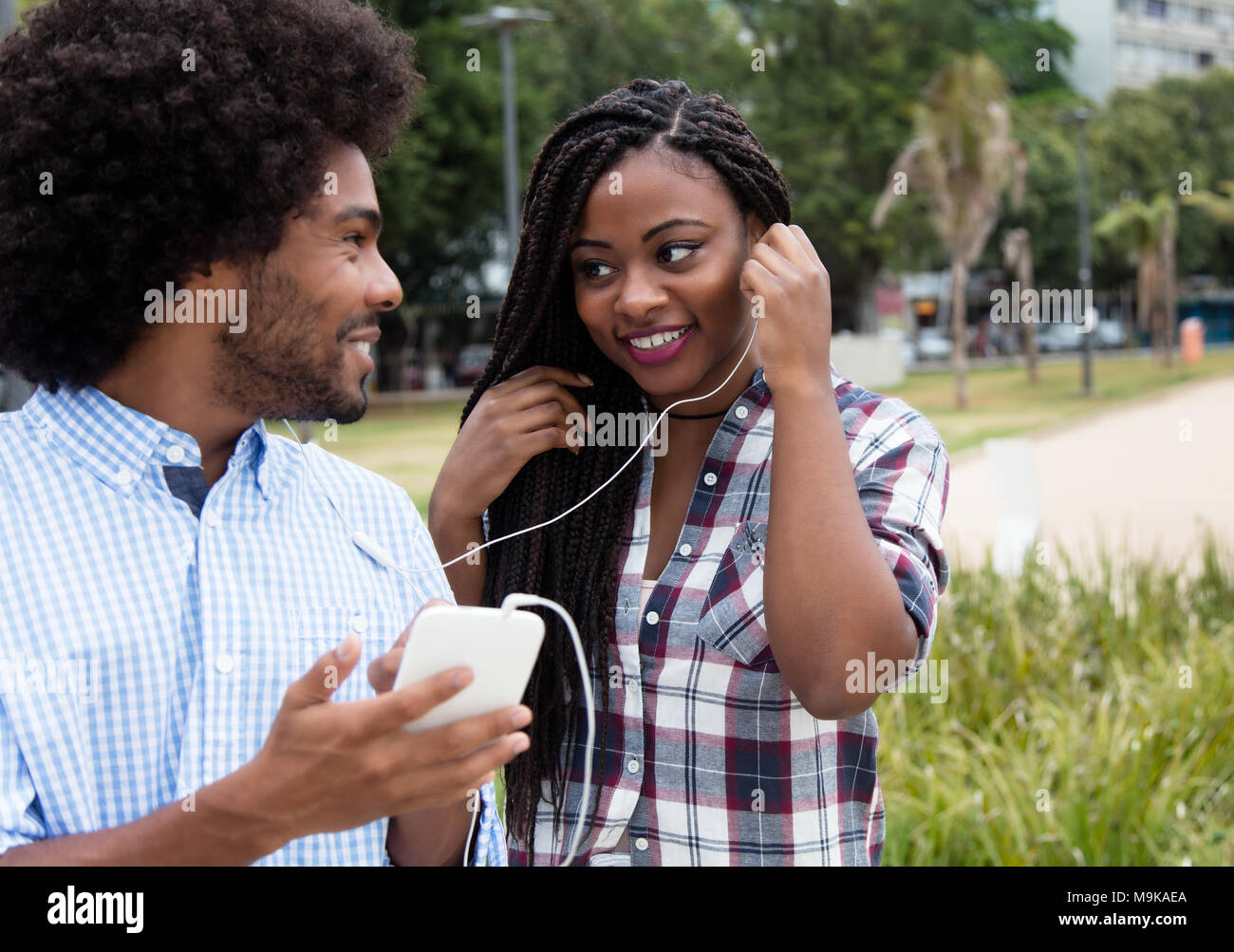 African American donna gode di musica con hipster amico all'aperto nella città Foto Stock