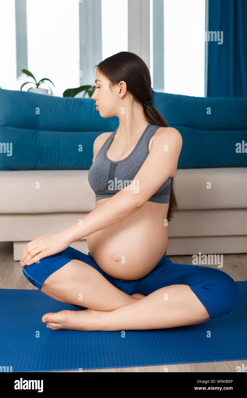 Donna incinta facendo esercizi yoga a casa. Gravidanza ginnastica in gravidanza, uno stile di vita sano concetto Foto Stock