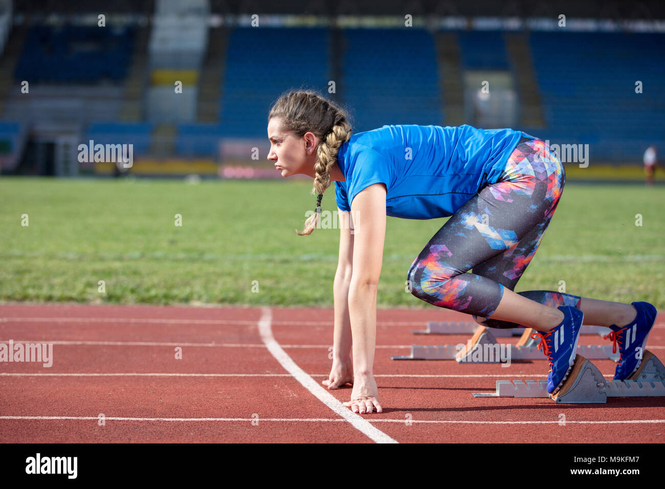 Atleta femminile in esecuzione sulla pista da corsa in una giornata di sole Foto Stock