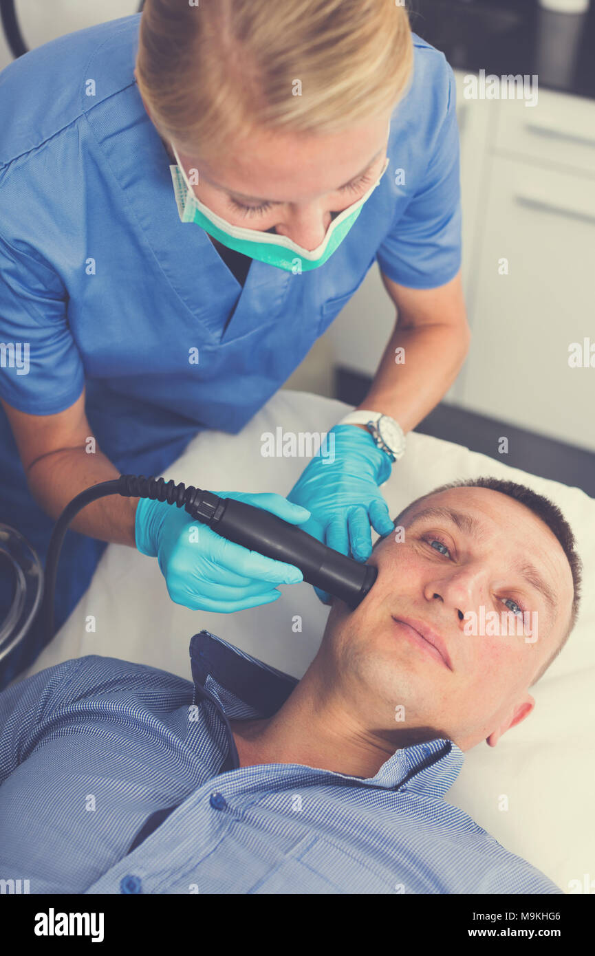 Medico donna sta facendo il vuoto procedura di sollevamento per la pelle del viso a paziente in estetic clinica. Foto Stock