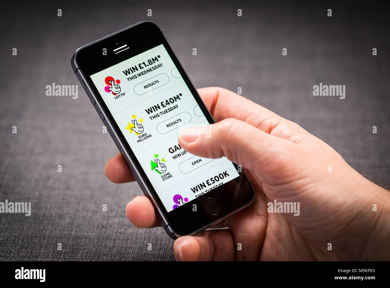 Un uomo con la lotteria nazionale app su un iPhone Foto Stock
