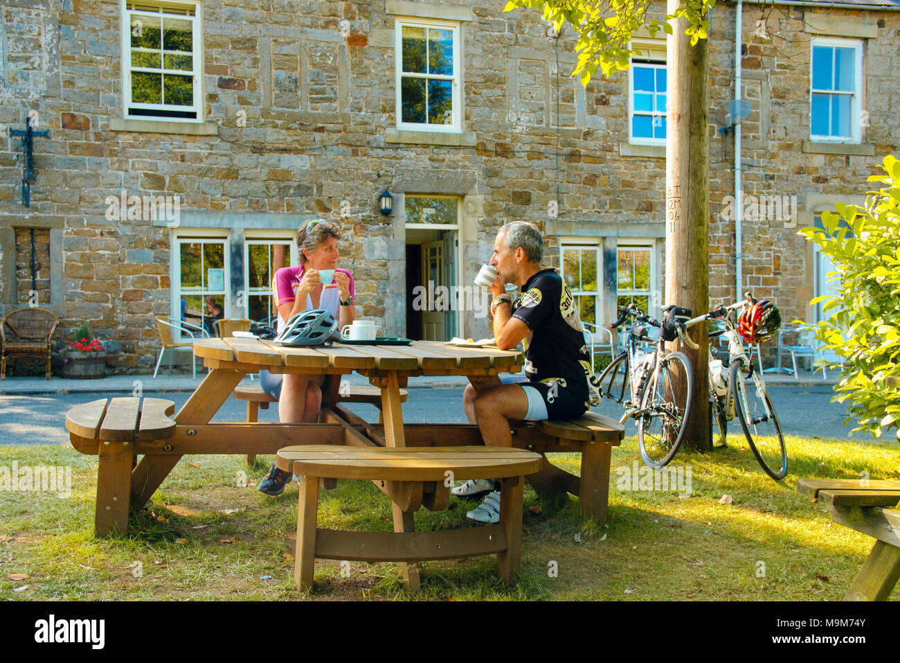 Due ciclisti prendere una pausa al di fuori di una caffetteria in Gilsland, Cumbria, vicino al Vallo di Adriano Foto Stock