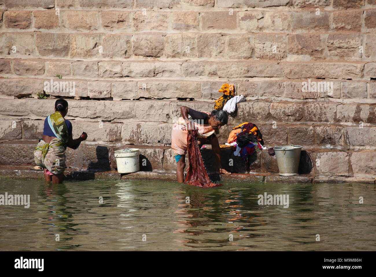 Donna indiana il lavaggio della biancheria e stoviglie sul fiume - inderin beim waschen von Kleidung und geschirr am fluss Foto Stock