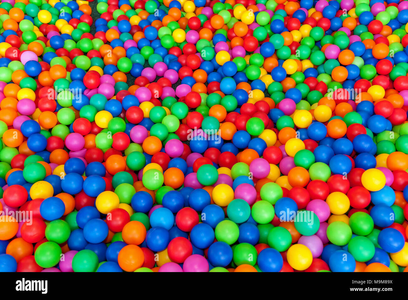 Un sacco di palle colorate in un parco giochi ball pool.la sfera con  coloratissime palle in plastica nei bambini di un centro di  intrattenimento. Piscina con sfere luminose sullo sfondo Foto stock -