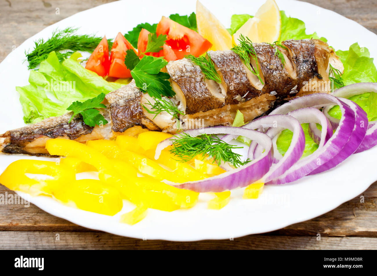 Nasello Pesce al forno con le verdure su una piastra Foto Stock
