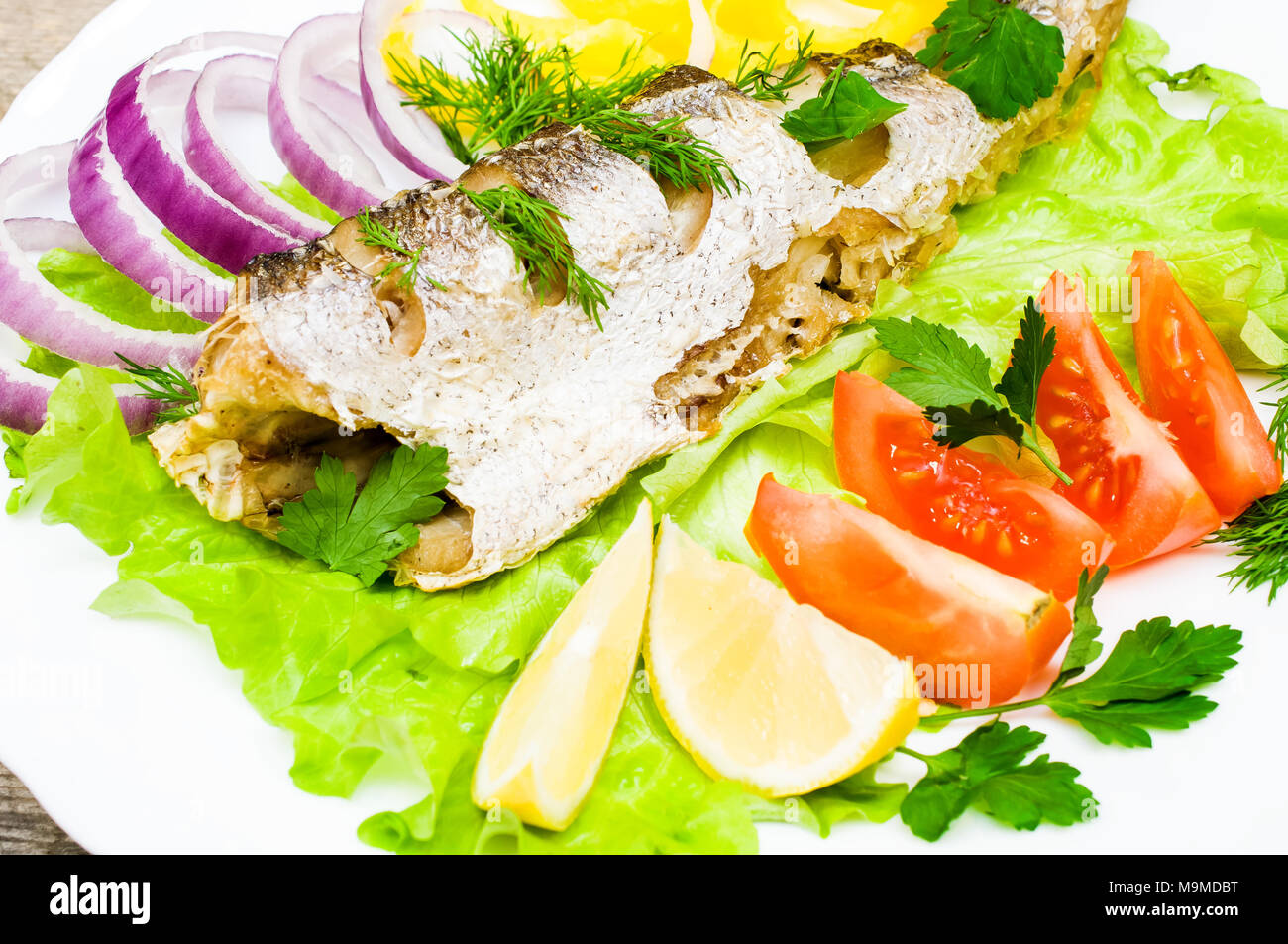 Nasello Pesce al forno con le verdure su una piastra Foto Stock