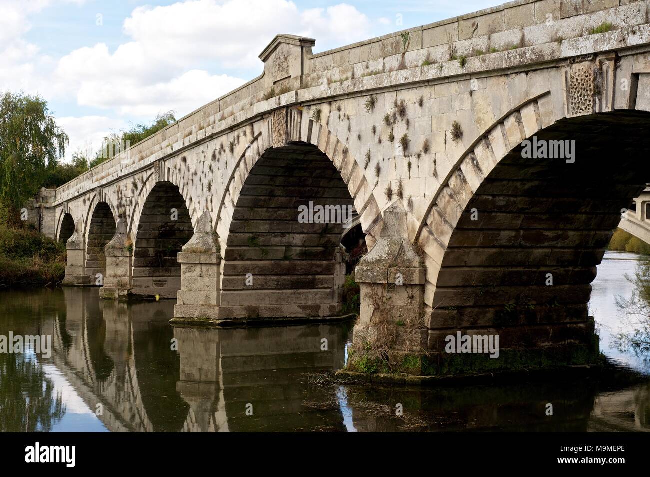Il ponte di pietra a Atcham Shrewsbury, Inghilterra oltre il fiume Severn che mostra l'acqua che scorre sotto decorativi archi scolpiti in autunno Foto Stock
