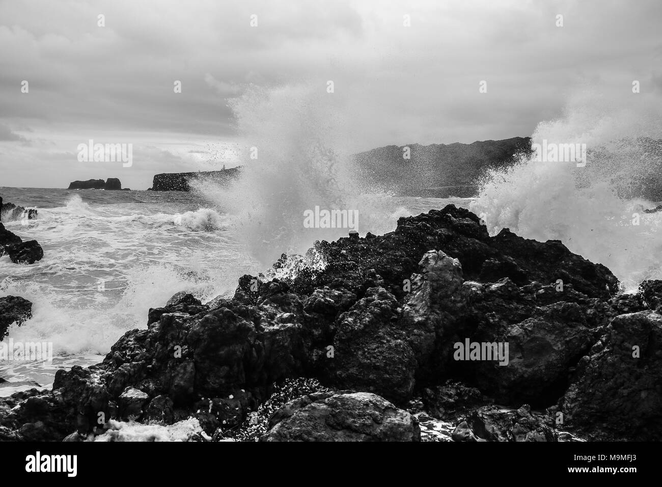 Onde infrangersi contro un oceano rocce, la spruzzatura di nebulizzazione in aria Foto Stock