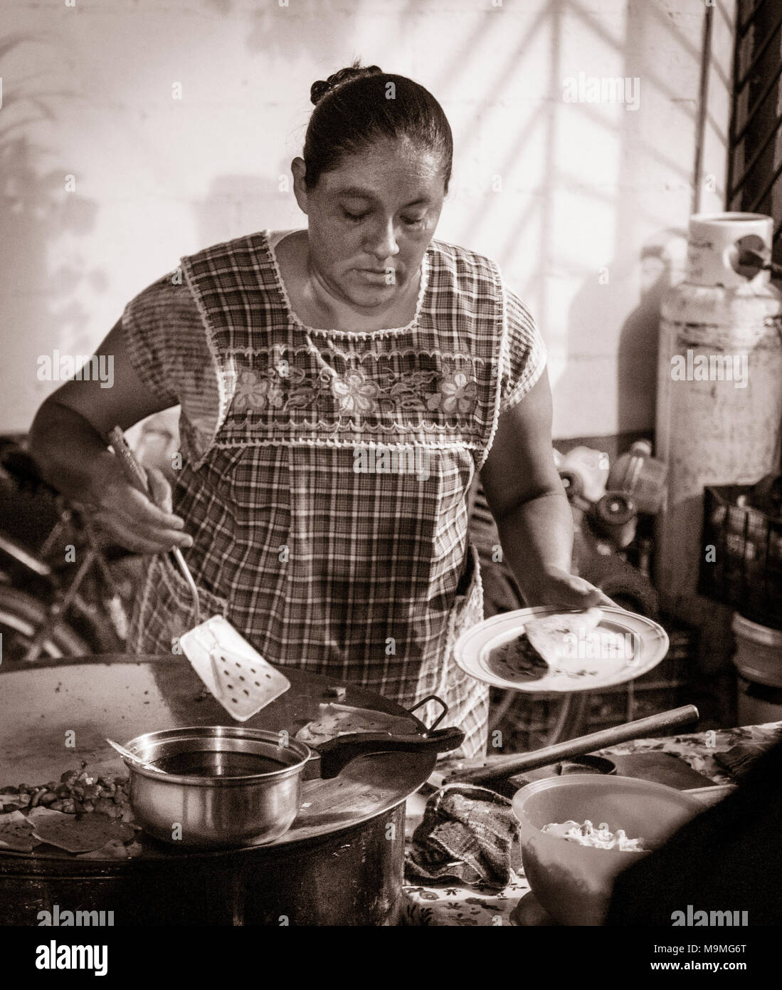 La cottura gli snack serali: una donna si riscalda snack dalla sua strada in stallo Chemuyil. Foto Stock
