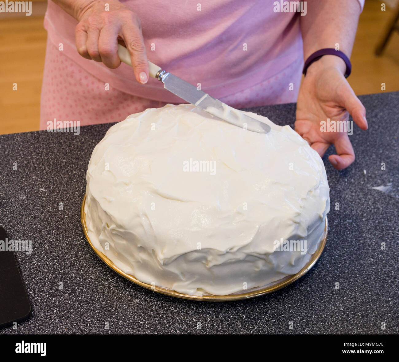 Glassa e decorazione di una torta di carote: Spalmare la glassa bianca con un coltello. Foto Stock
