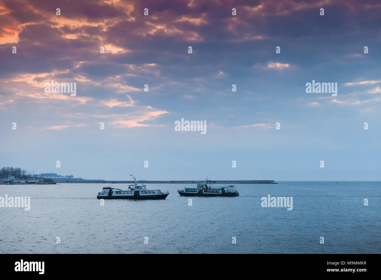 Due piccole navi passeggeri andare sotto il colorato del cielo della sera. Paesaggio di Sevastopol Bay in sunset Foto Stock