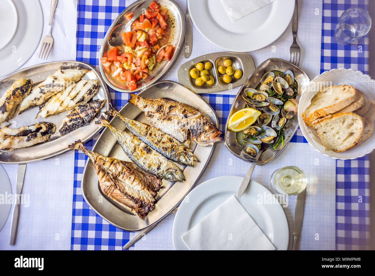 Coperti da tavola con le vongole deliziosa servita su argenteria, vino bianco, insalata di pomodoro, pane e olive da sopra, Portogallo Foto Stock
