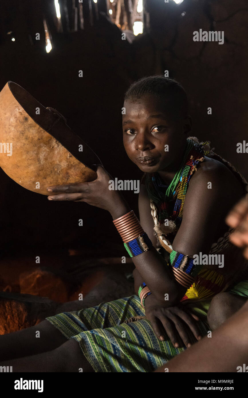 Donna di bere da calabash, seduto nella capanna di fango, Hamer tribe, Turmi, regione del sud unite, Etiopia Foto Stock