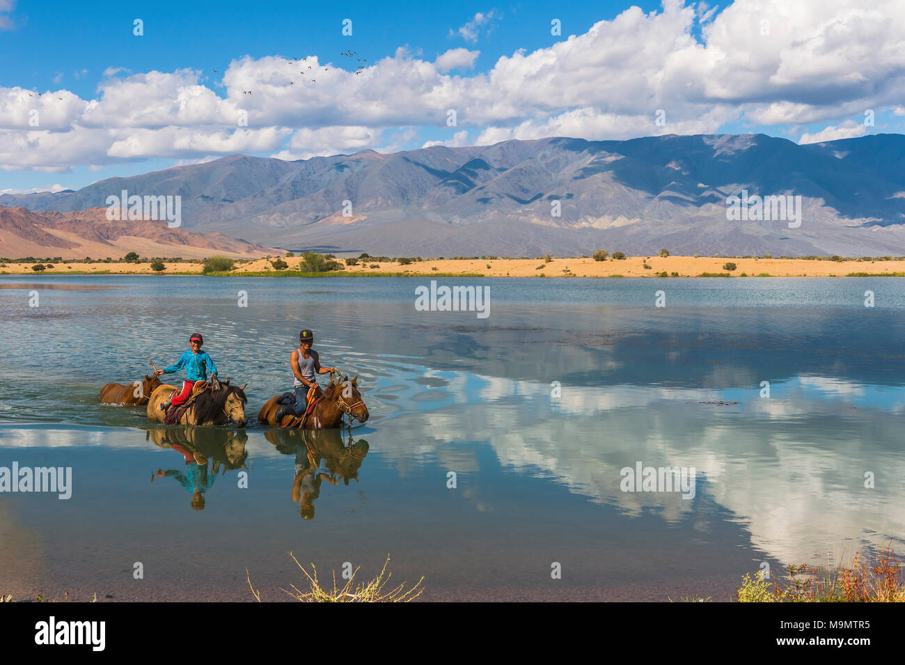 I bambini nomadi su cavalli attraversando il fiume Tuul durante il periodo estivo, Gorkhi-Terelj Parco Nazionale, Mongolia Foto Stock