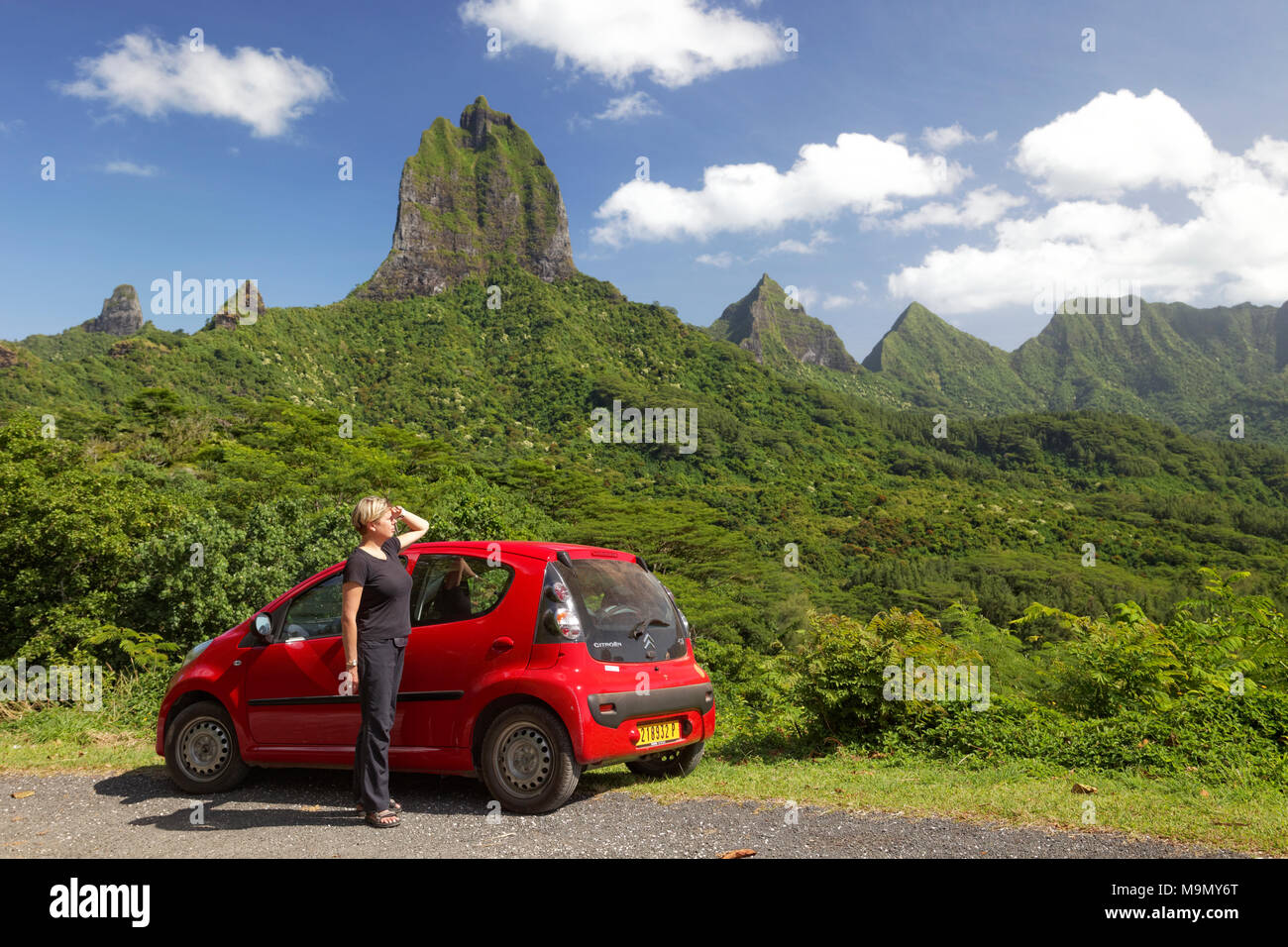 Donna con auto rossa al Belvedere vantage point, green mountain range con vegetazione verde e picchi più alti, Mont Tohiea, 1207 m Foto Stock