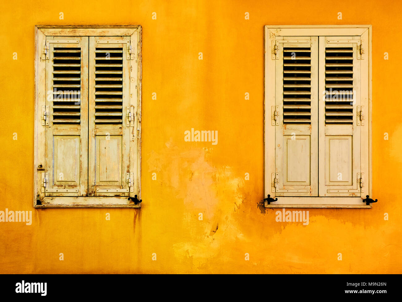 Parete gialla con due finestre con persiane nel quartiere Plaka a Atene, Grecia Foto Stock