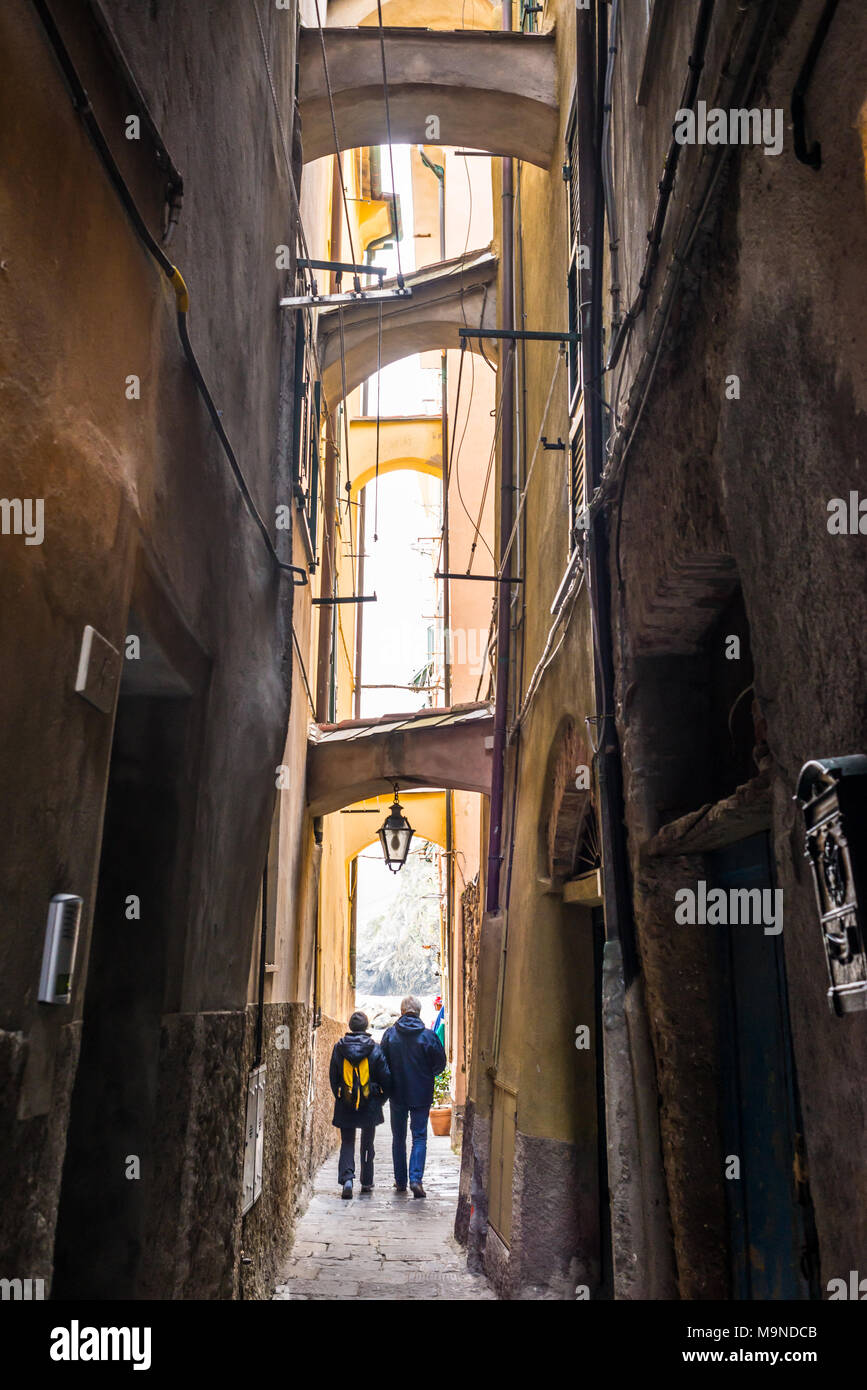 Due turisti senior giovane camminando per uno stretto vicolo buio in un italiano medievale città tradizionale Foto Stock