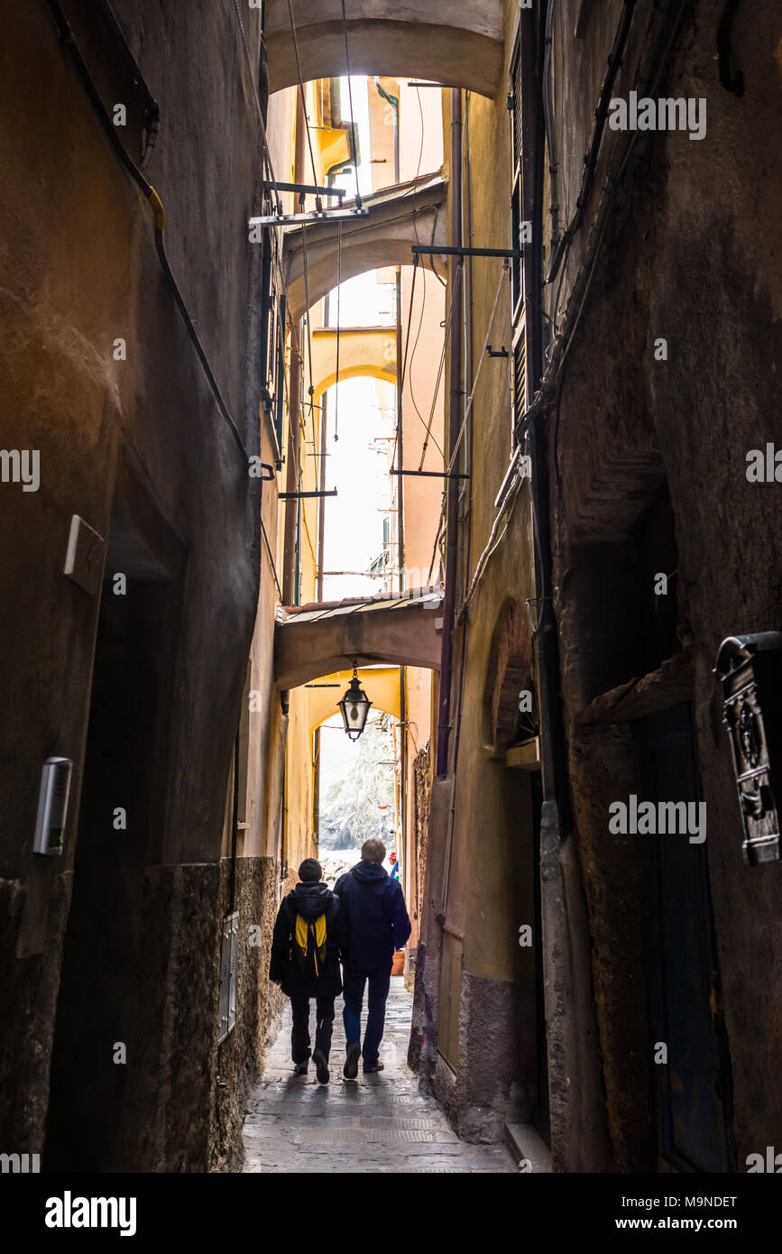 Due turisti senior giovane camminando per uno stretto vicolo buio in un italiano medievale città tradizionale Foto Stock