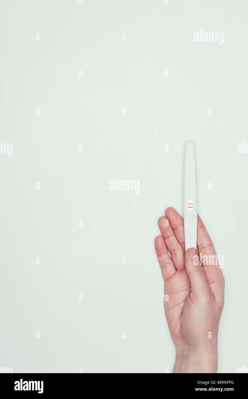 Vista parziale di donna con test di gravidanza in mano isolato su grigio Foto Stock